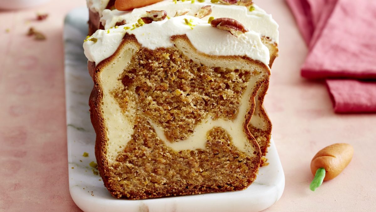 Draufsicht, leicht schräg: Ein angeschnittener Kastenkuchen auf einer rechteckigen Form aus Porzellan.