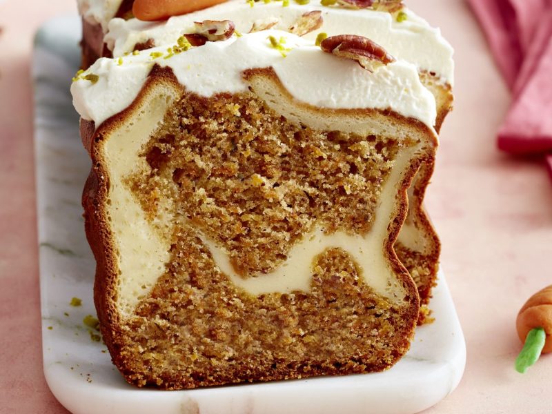 Draufsicht, leicht schräg: Ein angeschnittener Kastenkuchen auf einer rechteckigen Form aus Porzellan.