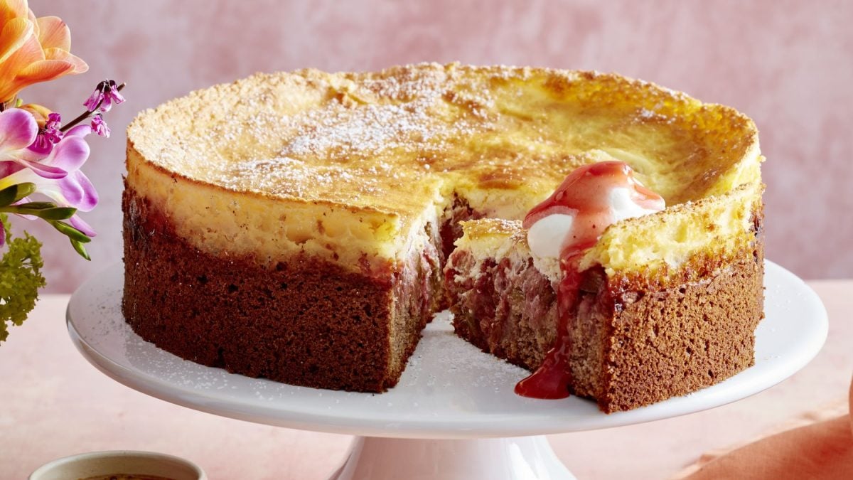 Auf einer runden hellen Kuchenplatte steht ein angeschnittener Kuchen.