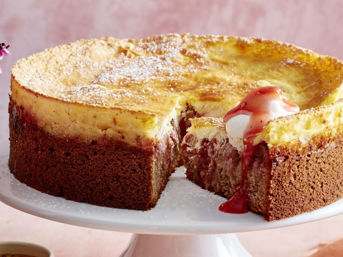 Auf einer runden hellen Kuchenplatte steht ein angeschnittener Kuchen.
