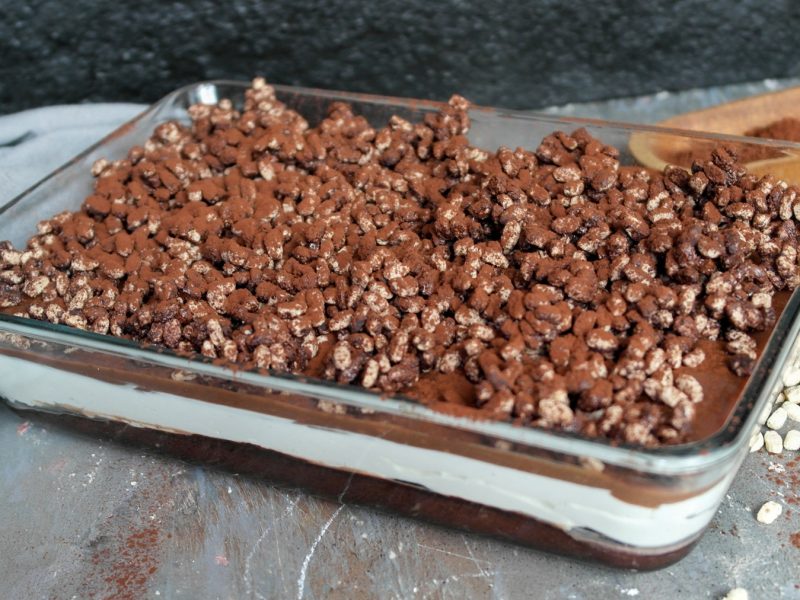 Eine Glasbackform mit dem Kuchen auf einem grauen Steintisch mit schwarzem Hintergrund.