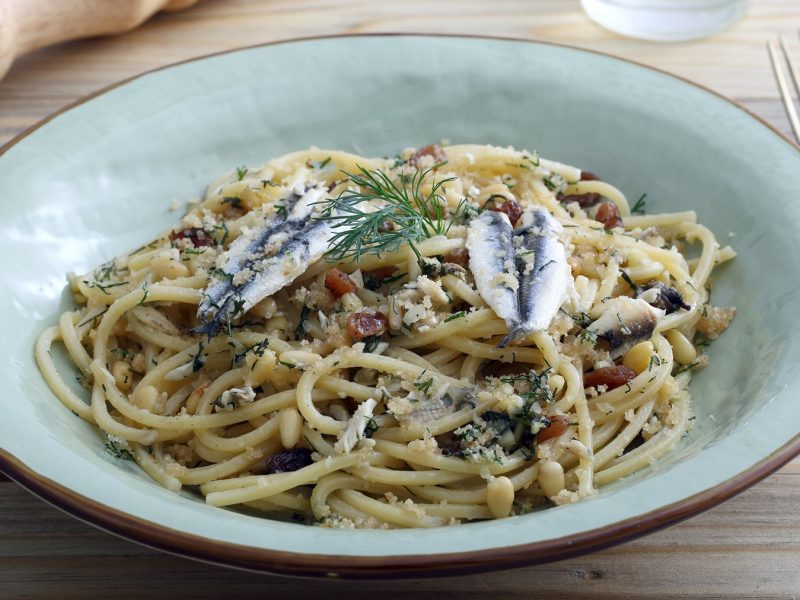 Ein Teller Pasta con le sarde, mit Pinienkernen, Rosinen und Kräutern, bestreut mit gerösteten Semmelbröseln und Fenchelgrün.