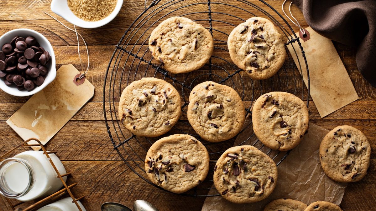 Frisch gebackene Sauerteig-Cookies kühlen auf einem Gitter aus, umgeben von Schokolade, Zucker und Milchflaschen.