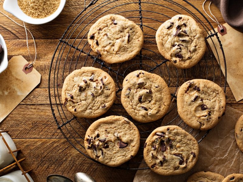 Frisch gebackene Sauerteig-Cookies kühlen auf einem Gitter aus, umgeben von Schokolade, Zucker und Milchflaschen.