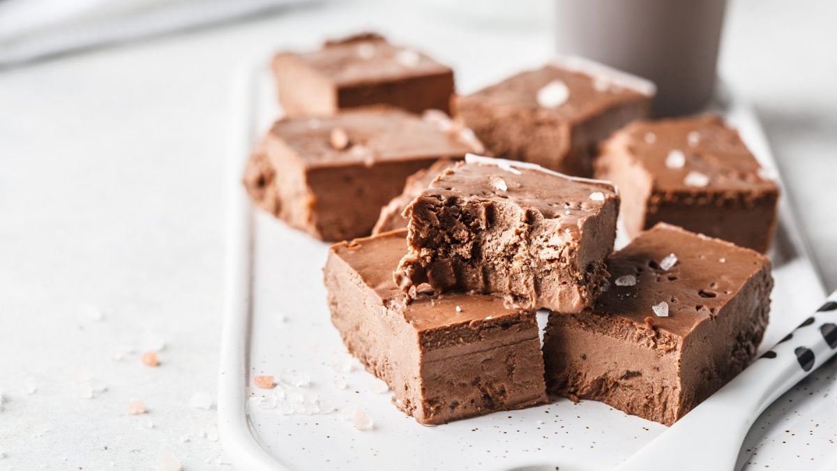 Schokoladige Fudge-Stücke mit zarter Textur und Salzflocken liegen verführerisch auf einer weißen Keramikplatte.