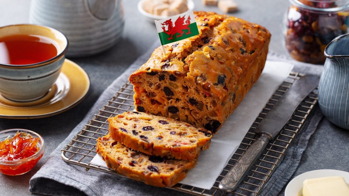 Draufsicht, schräg: Ein gedeckter Tisch mit einer Tasse Tee, Marmelade und einem aufgeschnittenen Früchtebrot Bara Brith aus Wales.