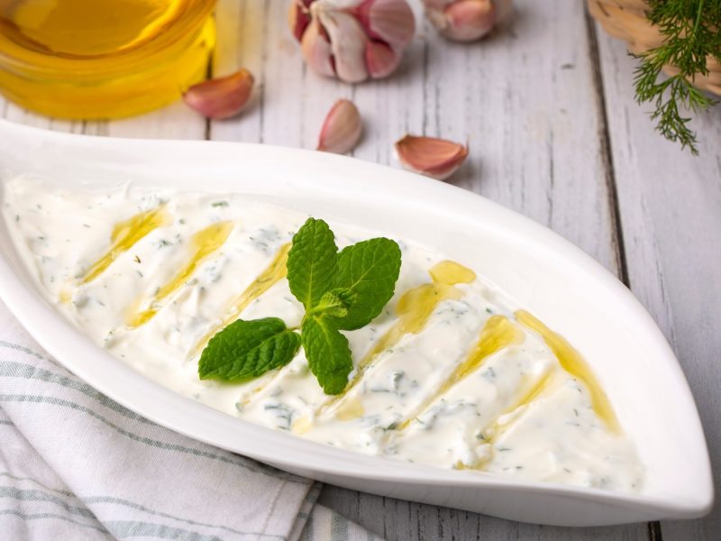 Draufsicht: Helle Form mit dem türkischen Joghurt-Dip Haydari auf einem Tisch.
