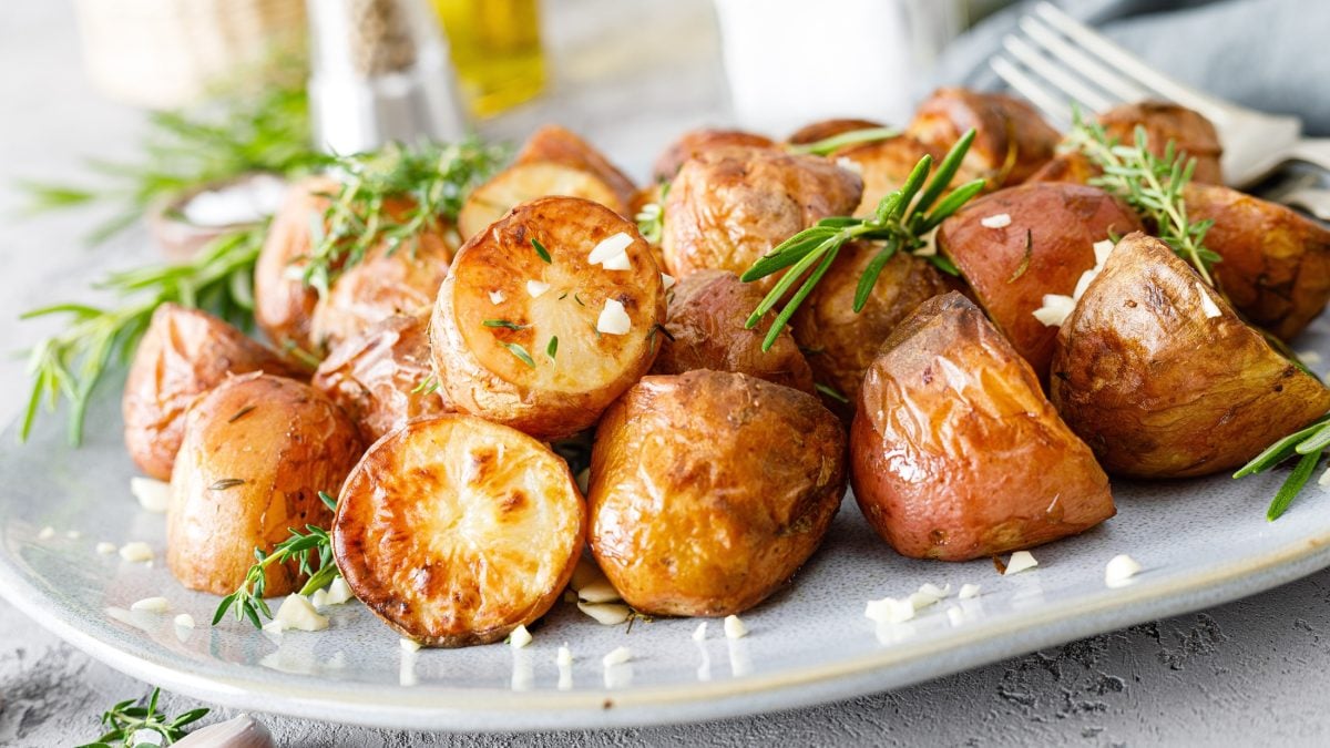 Frontal: Gegarte Kartoffeln auf einer hellen Porzellanschale. / Rustikaler Untergrund.