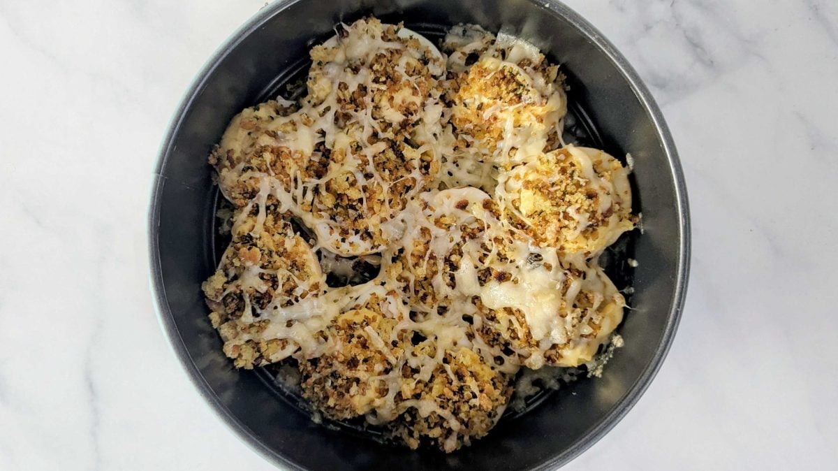 "French Onion Soup" gefüllte Eier in einer runden Auflaufform auf weißem Marmor.