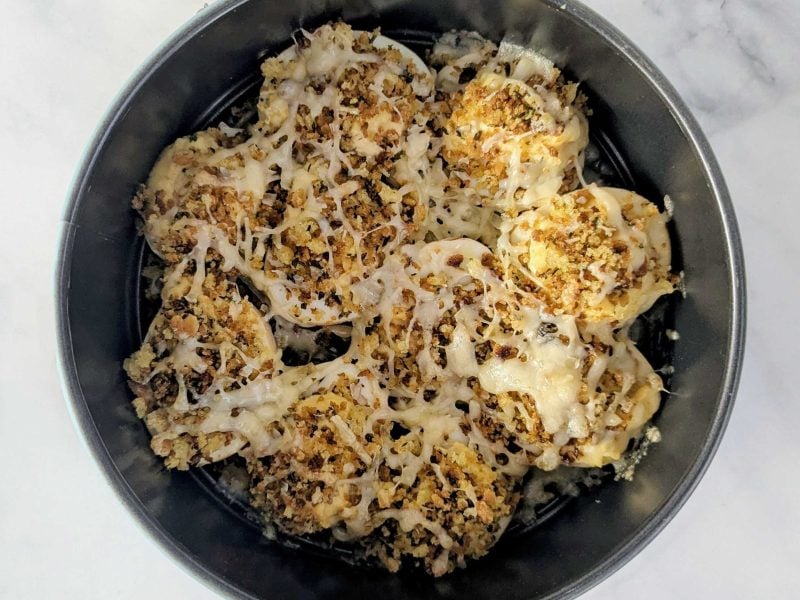 "French Onion Soup" gefüllte Eier in einer runden Auflaufform auf weißem Marmor.