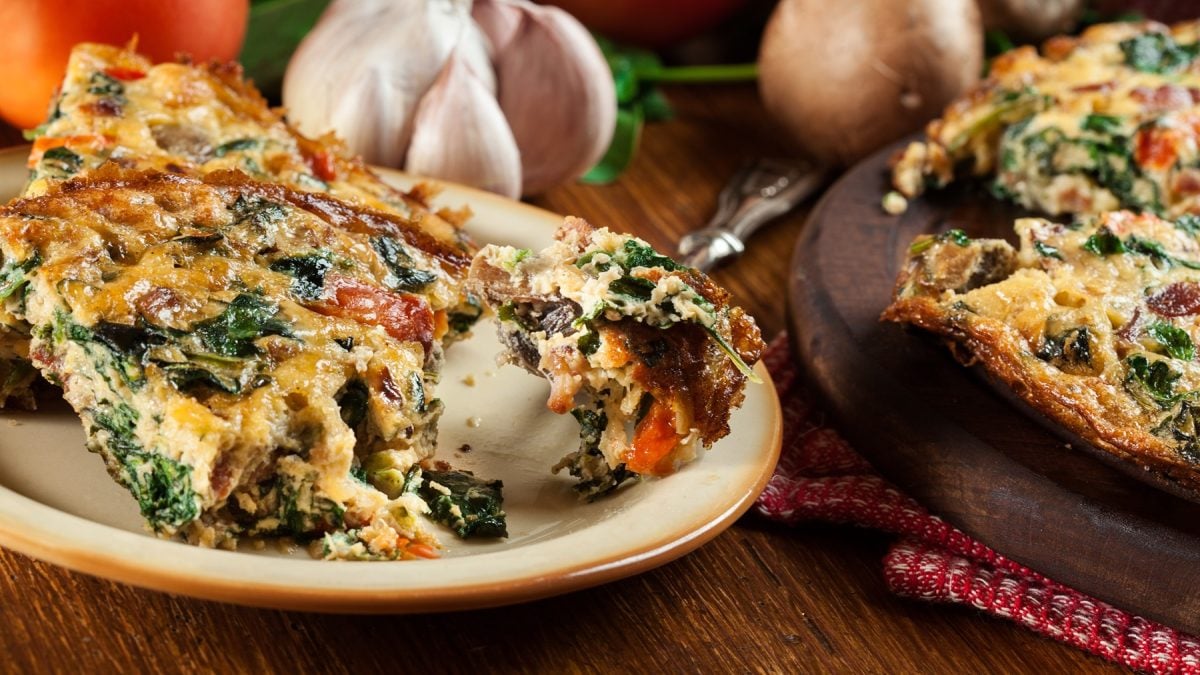 Zwei Teller mit dem Kartoffelkuchen auf einem dunklen Holztisch von der Seite fotografiert.