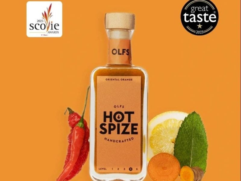 Schlichte Flasche scharfer Gewürzsauce mit Chilischote und Zitronenscheibe, ausgezeichnet mit Scovie- und Great-Taste-Awards.