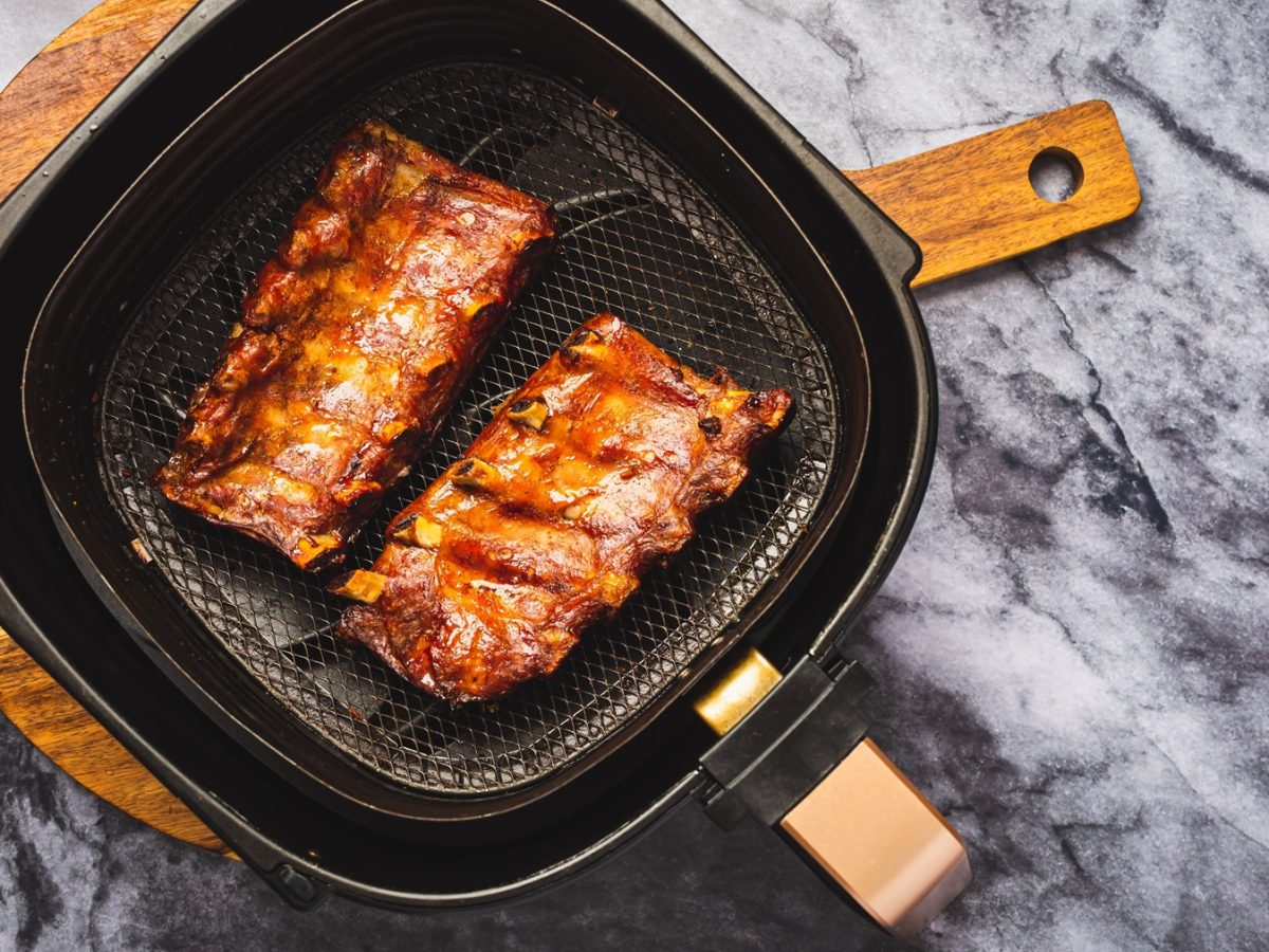 Zwei Stücke Spare Ribs im Airfryer auf einem Marmortisch direkt von oben fotografiert.