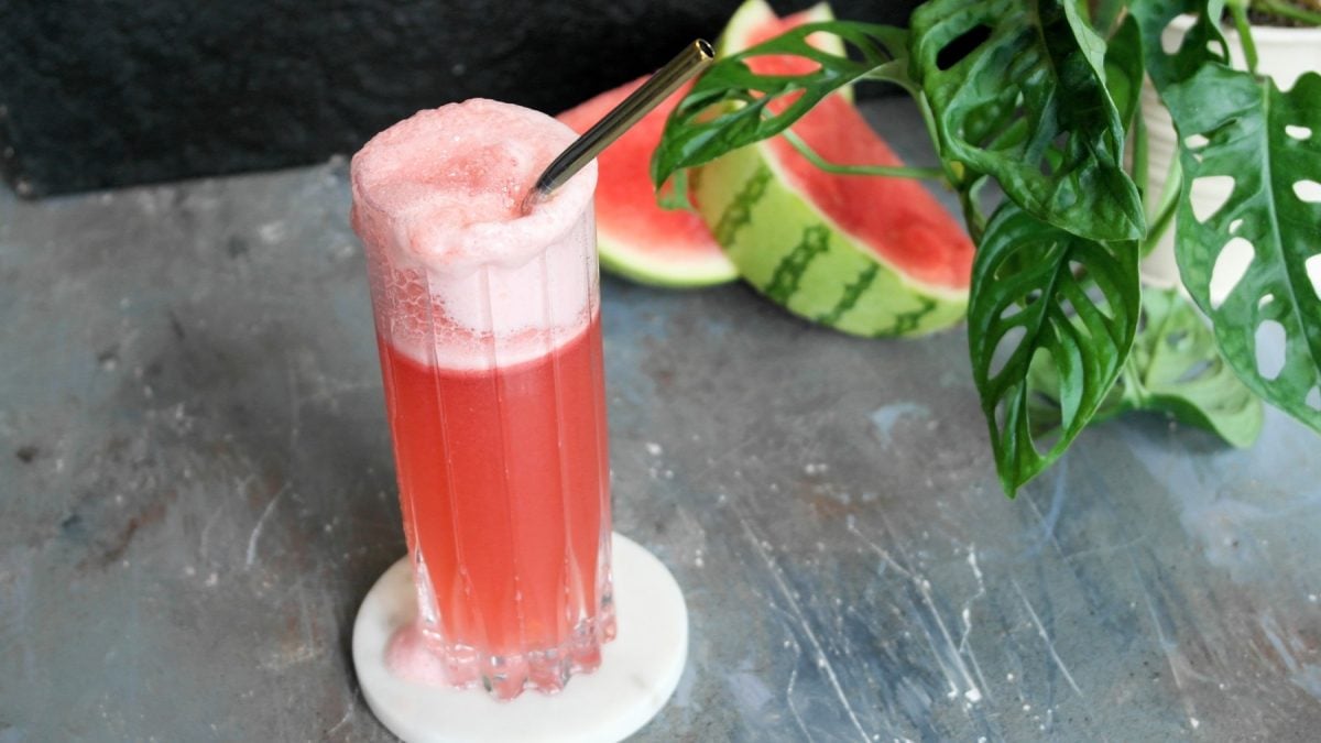 Ein Glas mit dem roten Cocktail auf einem grauen Untergrund. Alles von schräg oben fotografiert.