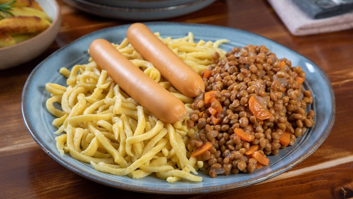 Draufsicht: Eine Teller Spätzle mit Linsen auf einem rustikalen Untergrund aus Holz.