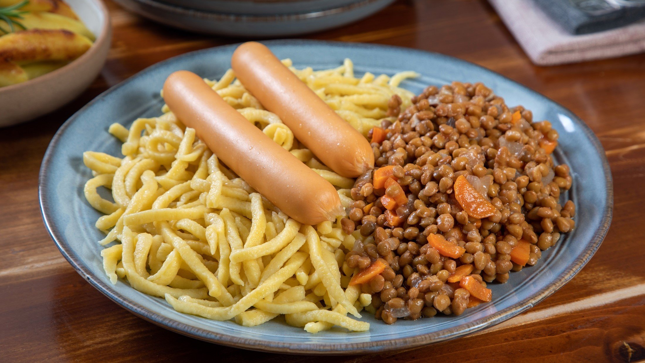 Draufsicht: Eine Teller Spätzle mit Linsen auf einem rustikalen Untergrund aus Holz.