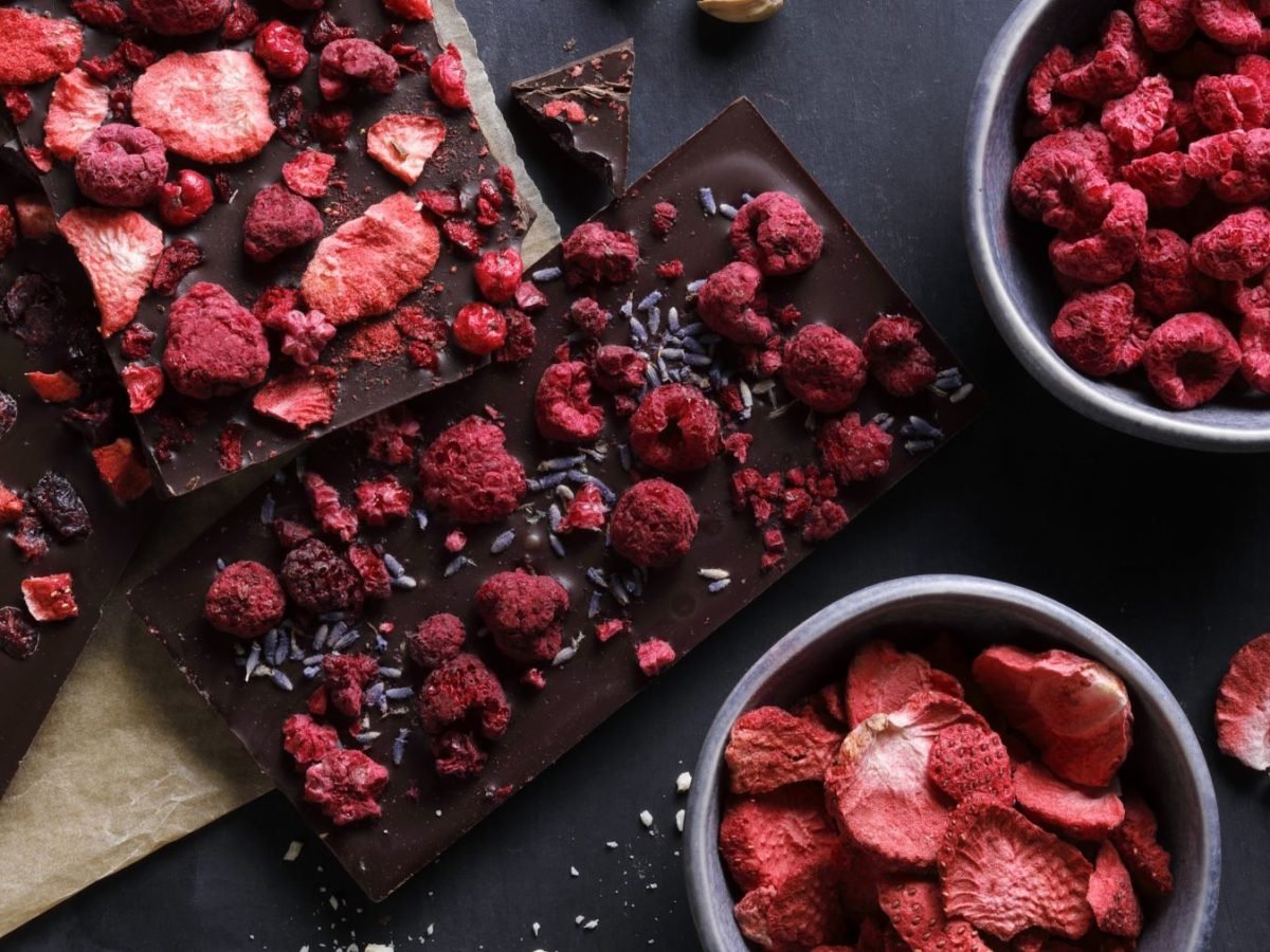 Selbstgemachte Erdbeer-Erdnussbutter-Schokolade in Stücke gebrochen, mit sichtbaren Schichten aus dunkler Schokolade, cremiger Erdnussbutter und knusprigen, gefriergetrockneten Erdbeeren als Topping.