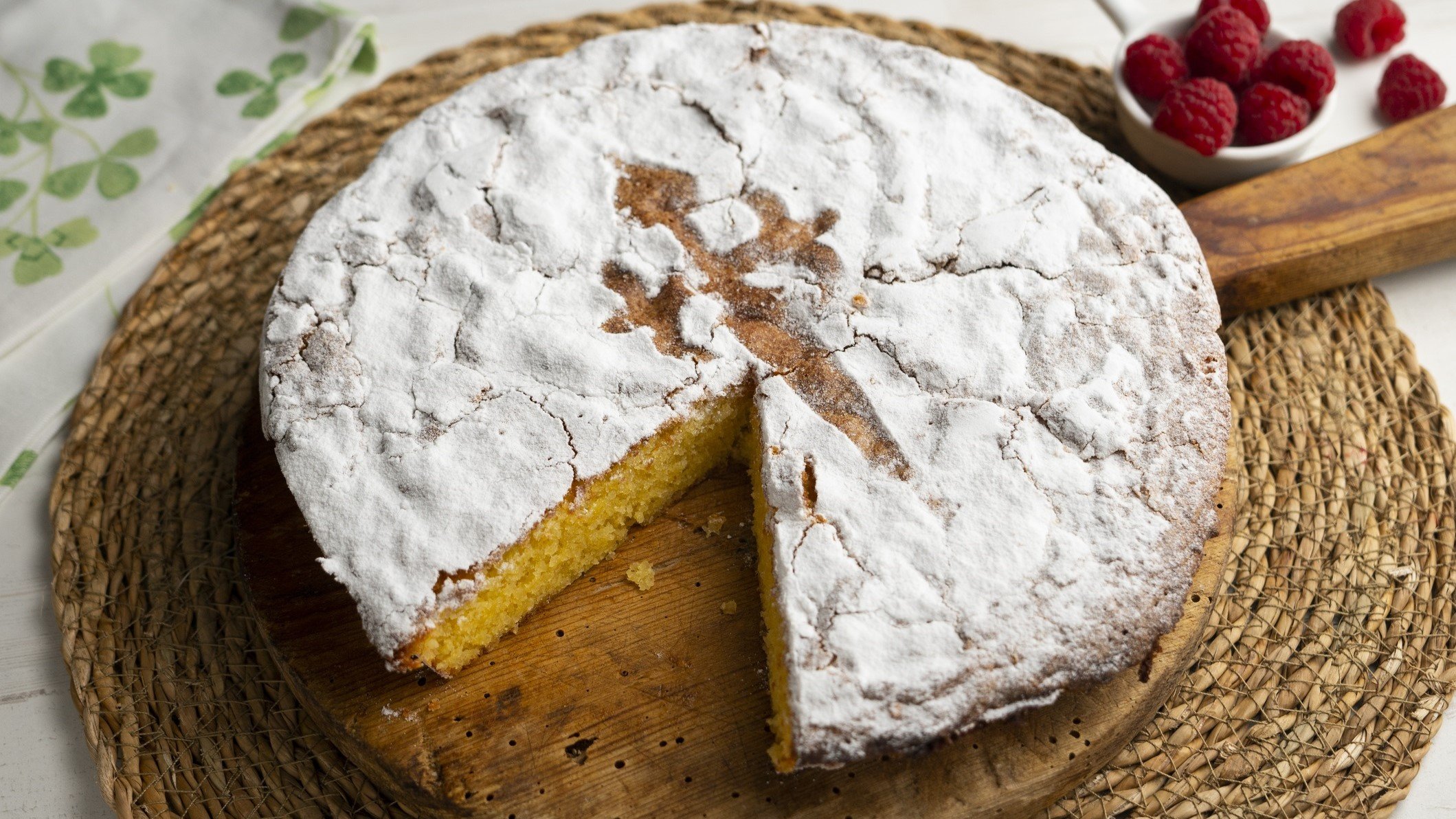 Eine angeschnittene Tarta de Santiago / bast-Unterlage / Draufsicht leicht schräg