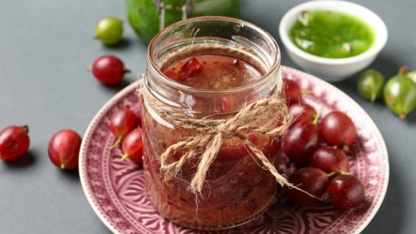 Zwei Gläser grüne und rote Stachelbeer-Marmelade / einzelne ganze Früchte. Draufsicht, leicht schräg.