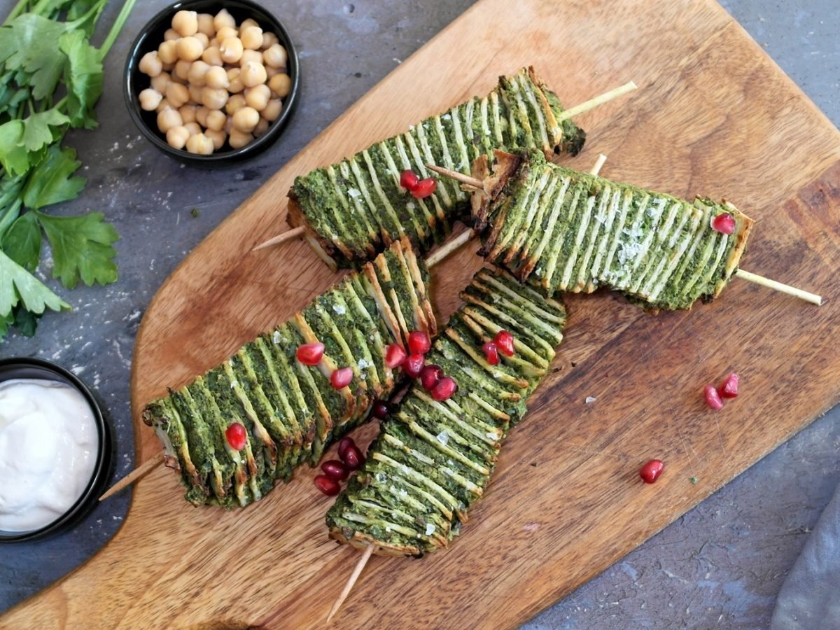 Mehrere Falafel-Spieße auf einem Holzbrett und grauem Steintisch direkt von oben fotografiert.